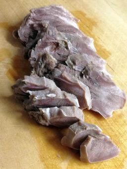 Keitetty peuran kieli viipaloituna leikkuulaudalla