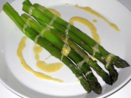 Vihreä parsa hollandaisekastikkeen kera lautasella