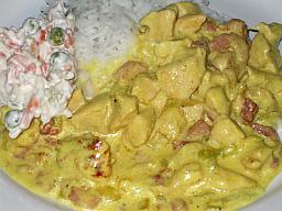 Broilerikastike tarjoiltuna riisin ja italiansalaatin kera lautasella