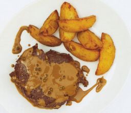 Grillattua entrecôtea pippurikastikkeen sekä lohkoperunoiden kera lautasella