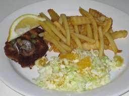 Kaali-appelsiinisalaatti wieninleikkeen sekä ranskalaisten perunoiden kera lautasella