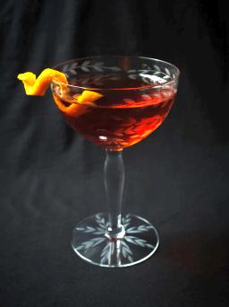 Martinez-cocktail, jossa giniä, kuivaa vermuttia ja Maraschinoa, koristeltuna kirsikalla ja sitruunankuorikiehkuralla