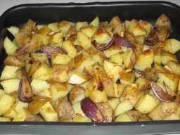 Ugnsrostad kryddad klyftpotatis i form med rödlök och vitlök