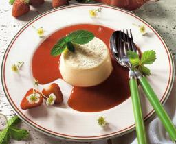 Pannacotta med jordgubbssås och mynta serverad på tallrik