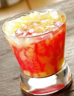 Tequila Sunrise cocktail korkeassa lasissa jäämurskalla ja grenadiiniraitojen kanssa