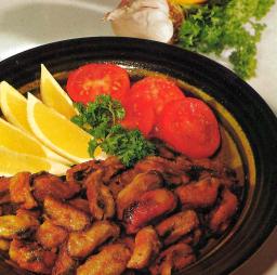 Valkosipulinmakuiset paistetut simpukat lautasella sitruunalohkojen kera