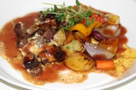 Yrttinen häränfilee ja portviinikastiketta paahdettujen kasvisten kera lautasella.