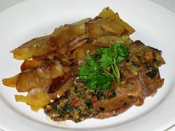 Lampaankyljykset raakana paistettujen perunoiden kera lautasella